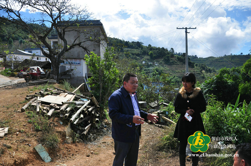 图为市残联杨学华副理事长与挂钩户交流